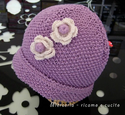 Cappellino neonato fatto ai ferri con fiori all’uncinetto